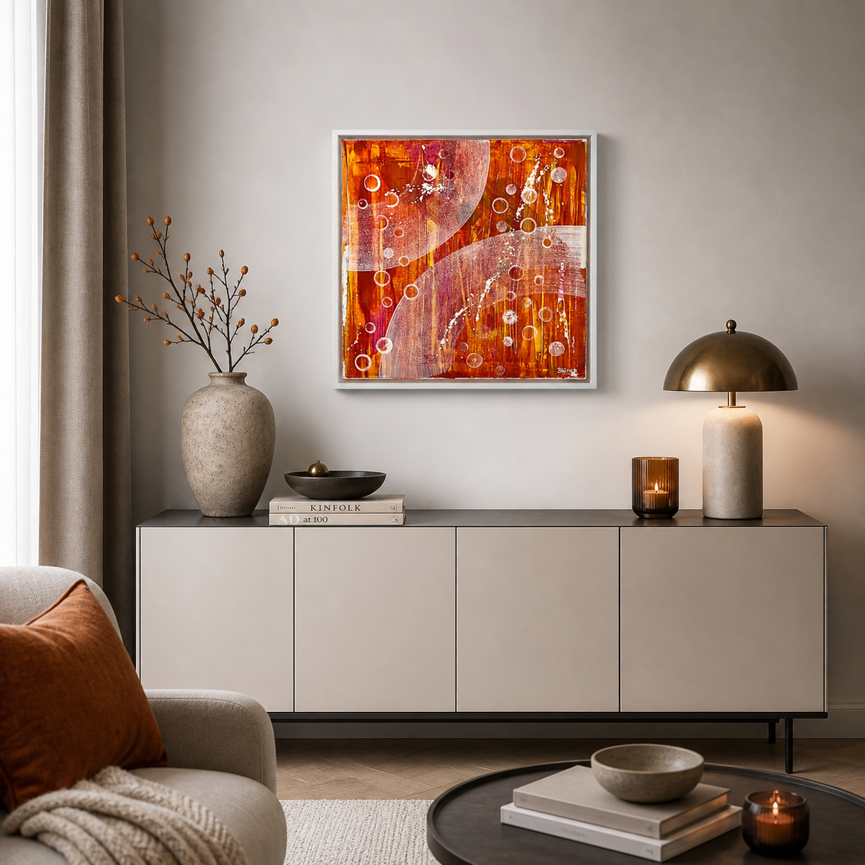 Handgemaltes Acrylbild in Orange und Rot mit abstrakten Kreisen über einer modernen Kommode in einem stilvoll eingerichteten Wohnzimmer – hochwertige Wanddekoration