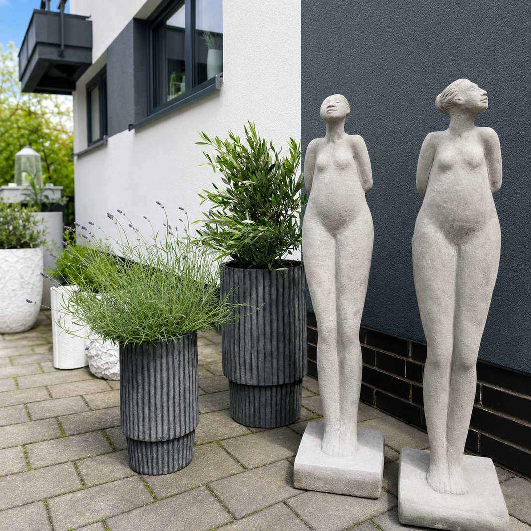 Moderne Gartenfiguren aus Steinoptik neben stilvollen Pflanzgefäßen und Lavendel vor einem modernen Outdoor-Bereich bei Atelier B.