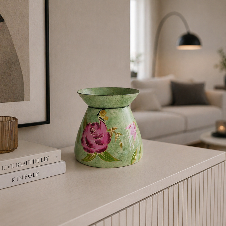 Handbemalte grüne Metallvase mit Blumenmotiv auf einer hellen Kommode in einem modern eingerichteten Wohnzimmer