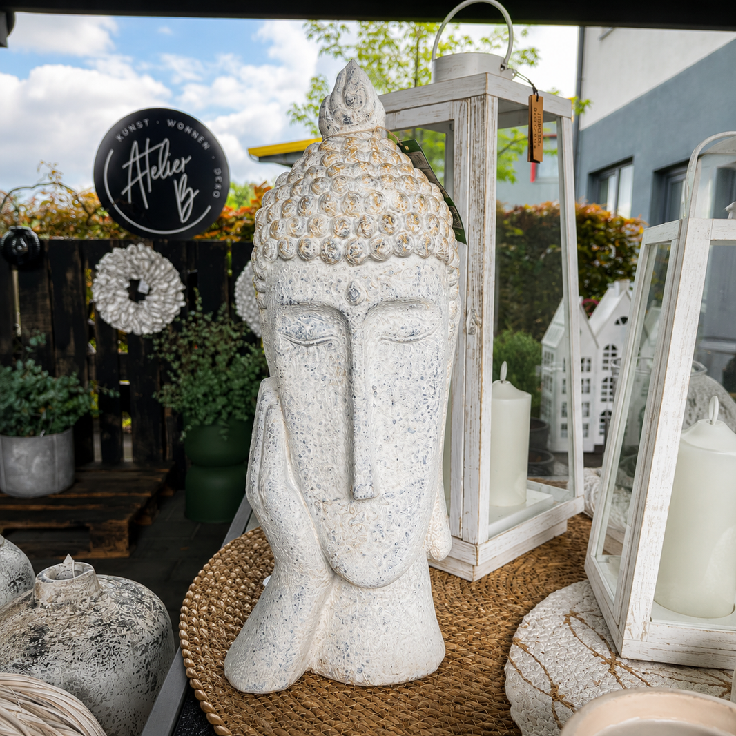 Weiße Buddha-Dekofigur auf einem dekorierten Outdoor-Tisch mit Laternen, Naturmaterialien und stilvoller Terrassendekoration bei Atelier B.