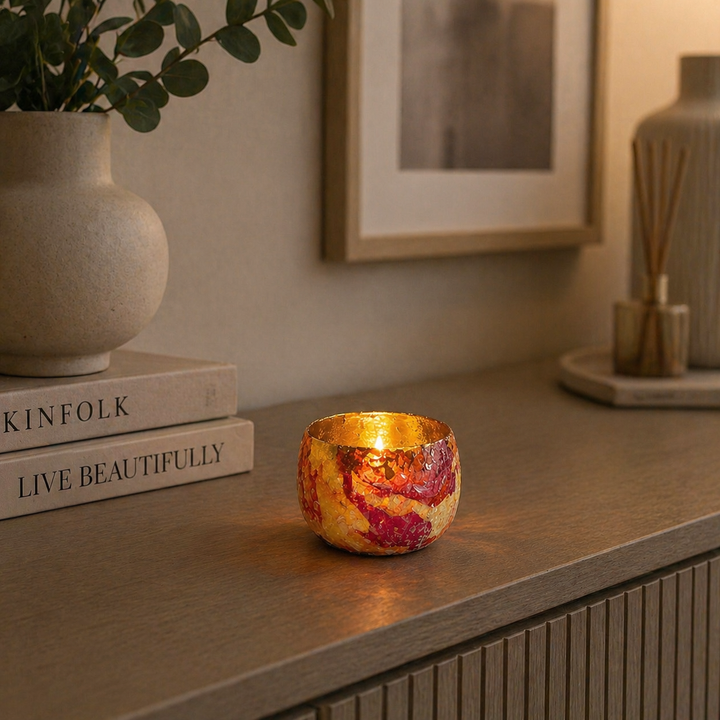 Kleiner Teelichthalter aus Glas mit goldener Innenfläche und Kerzenlicht auf Kommode im modernen Wohnzimmer