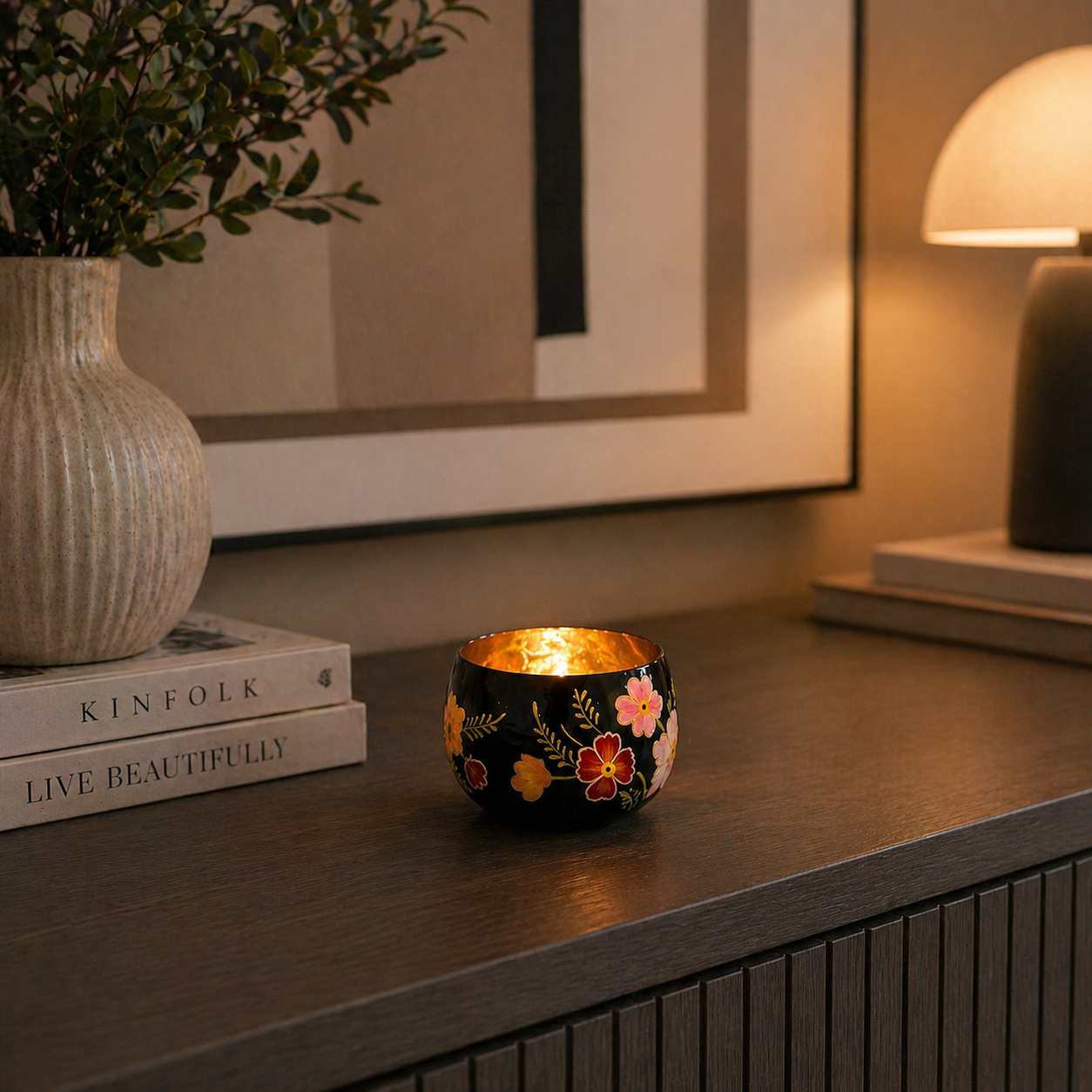 Kleiner Teelichthalter aus Glas in Schwarz und Gold mit Blumenmuster auf einer modernen Kommode im Wohnzimmer mit Kerzenlicht