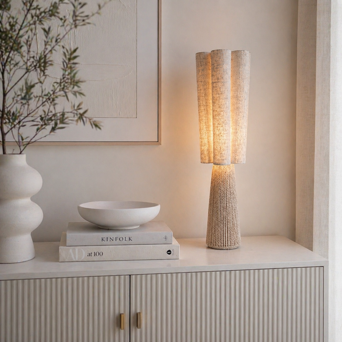 Moderne Tischlampe mit Stoffschirm in Naturoptik auf heller Kommode im minimalistischen Wohnstil dekoriert