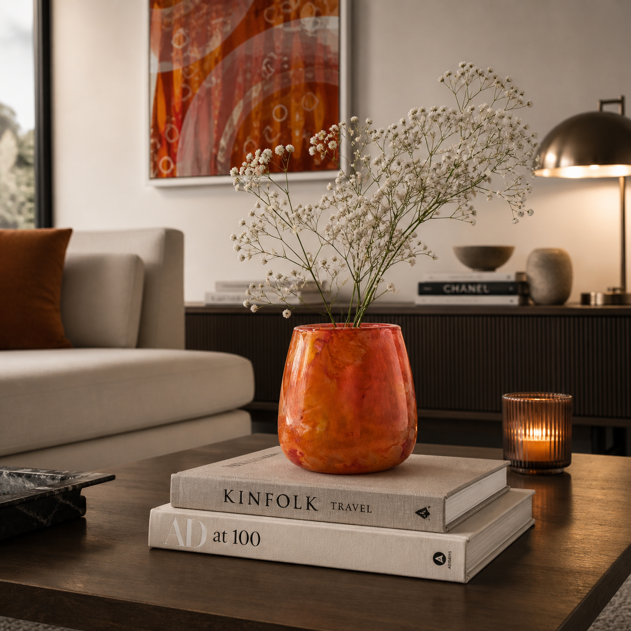 Modernes Windlicht aus Glas in Orange dekoriert mit Blumen auf einem Wohnzimmertisch in stilvoll eingerichtetem Wohnzimmer – vielseitig als Vase oder Kerzenhalter nutzbar