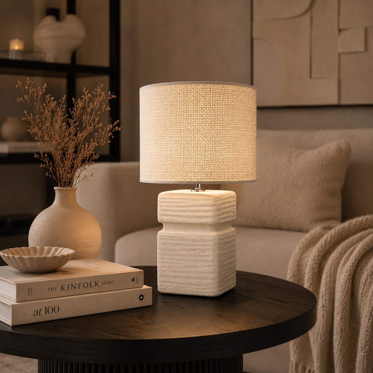 Elegante Keramik Tischlampe von Atelier B mit strukturierter Oberfläche und hellem Stoffschirm auf dunklem Wohnzimmertisch mit moderner neutraler Dekoration und gemütlicher Lichtstimmung.