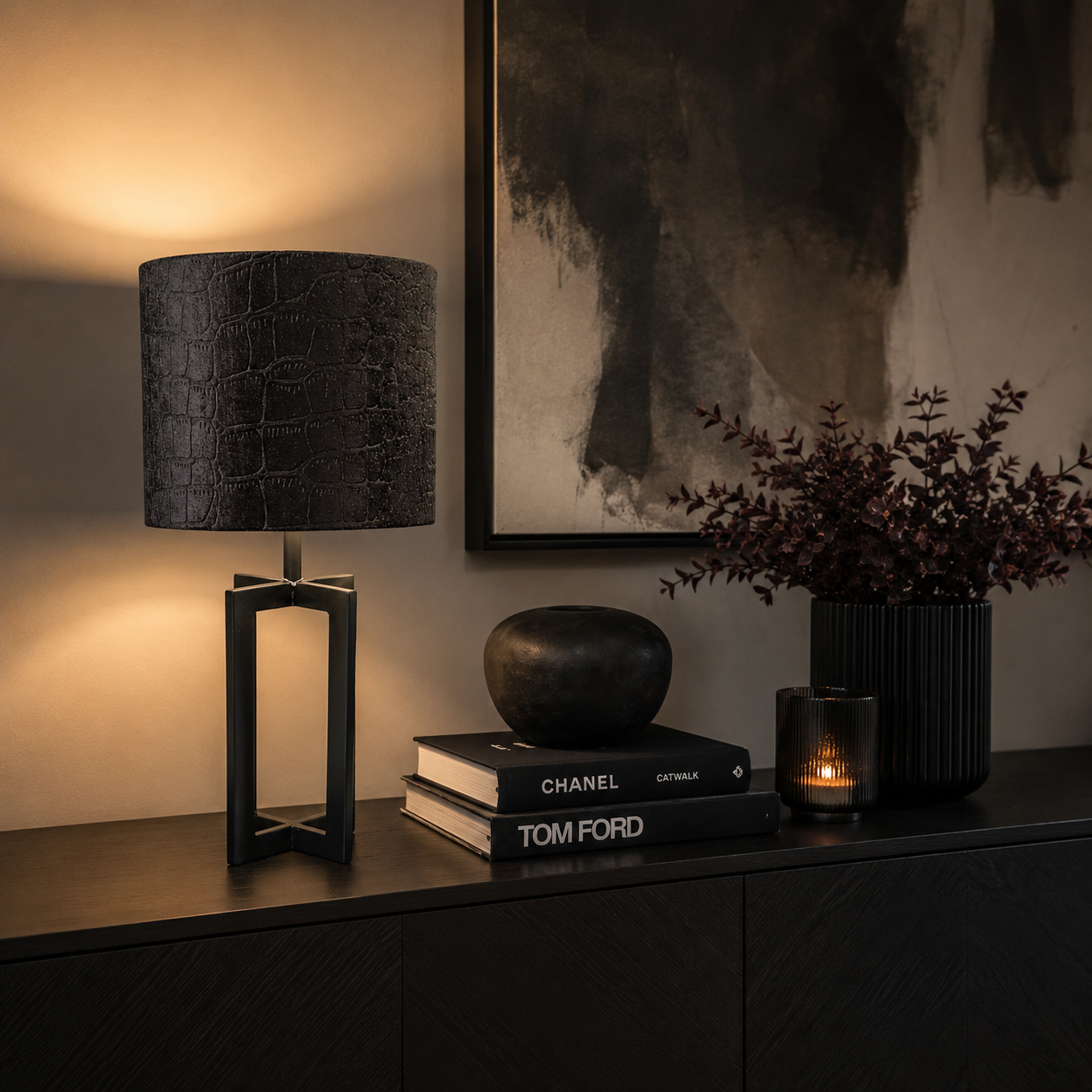 Schwarze Designer-Tischlampe von Atelier B mit strukturierter Stoffoberfläche und warmem Licht auf einem modernen Sideboard mit abgestimmter schwarzer Deko in stilvollem Wohnzimmer-Ambiente.