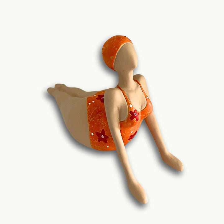 Moderne dekorative Frauenfigur in Orange liegend.