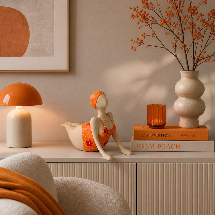 Moderne dekorative Frauenfigur in Orange liegend auf einer Kommode, stilvoll arrangiert in einem Wohnzimmer mit warmen orangenen Akzenten und eleganter Einrichtung