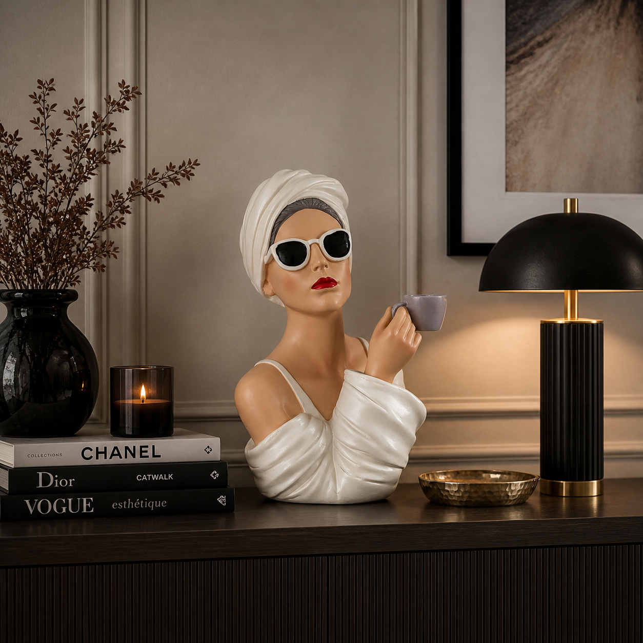 Moderne Dekofigur einer Frau mit Sonnenbrille und Handtuch, die eine Tasse hält, dekorativ auf einem Sideboard mit stilvollen Wohnaccessoires und warmer Beleuchtung