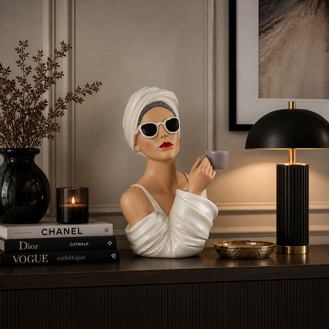 Moderne Dekofigur einer Frau mit Sonnenbrille und Handtuch, die eine Tasse hält, dekorativ auf einem Sideboard mit stilvollen Wohnaccessoires und warmer Beleuchtung