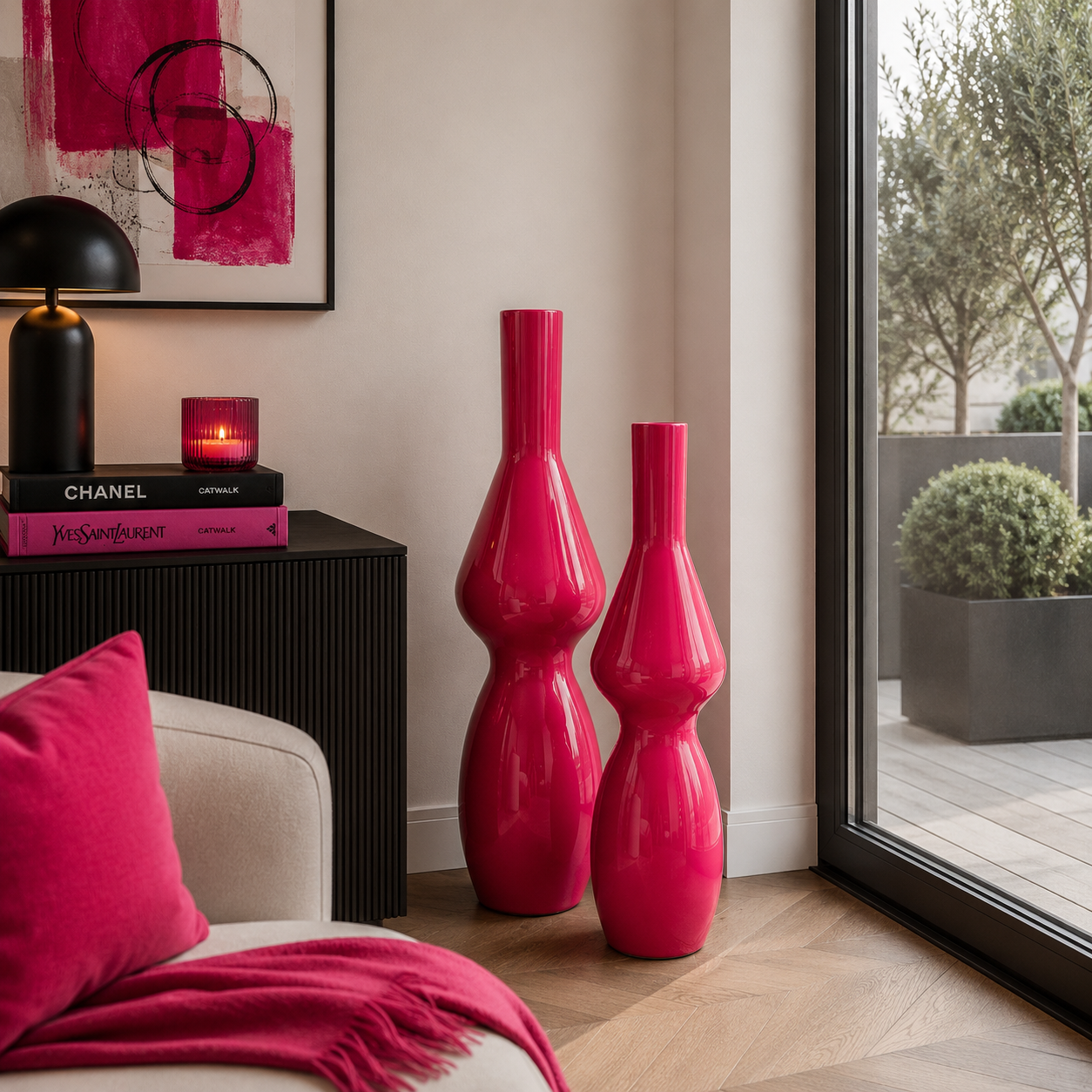 Moderne pinke Bodenvasen in einer eleganten Wohnzimmerecke mit schwarzen Möbeln, großem Fenster und stilvollen pinken Dekorationselementen.