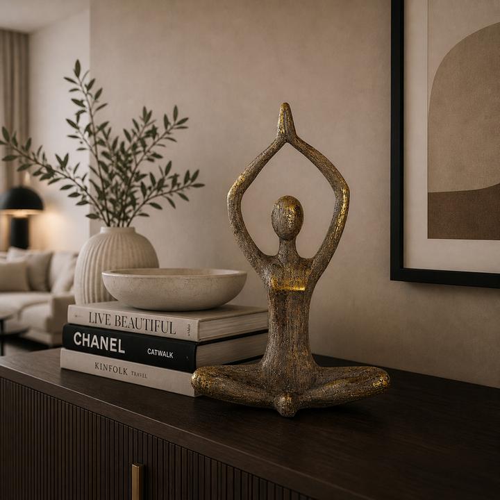 Meditierende Yoga Dekofigur aus Holz in Braun mit goldenen Akzenten auf einer stilvollen Kommode in einem modern eingerichteten Wohnzimmer mit warmer Beleuchtung